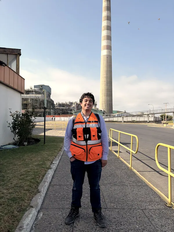 Ingeniero con chaleco reflectante en el patio de una planta, con la chimenea al fondo