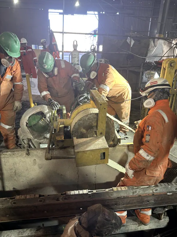Cuadrilla con respiradores trabajando sobre un equipo dentro de una fundición