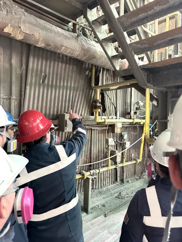 Ingenieros con casco y respirador revisando una línea de gas en la planta