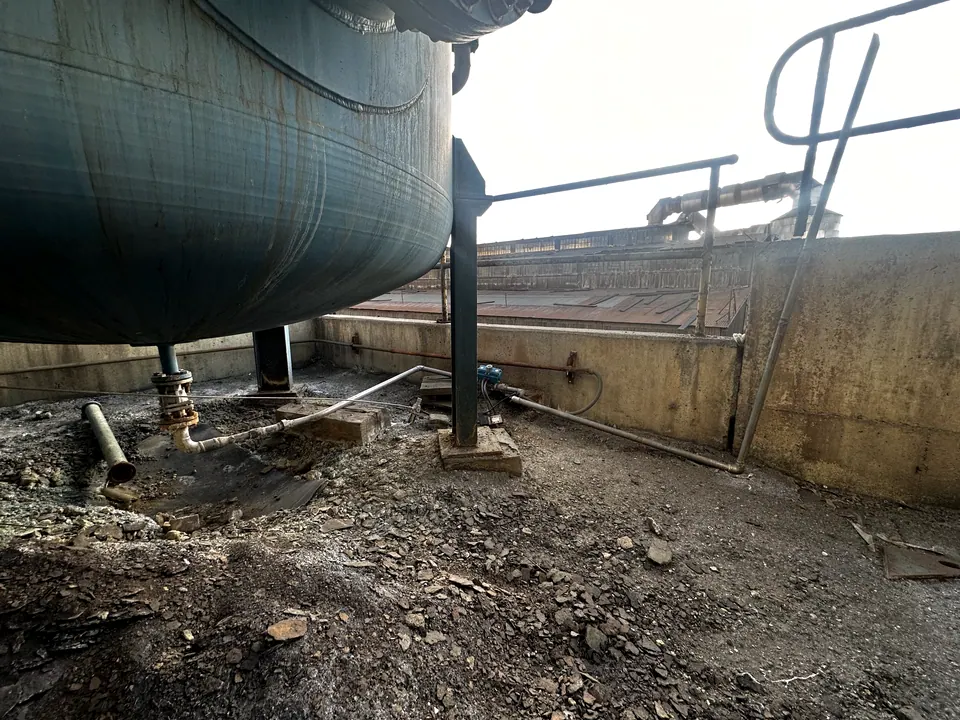 Base de un estanque de acero en una planta, con la baranda y la canaleta de derrames