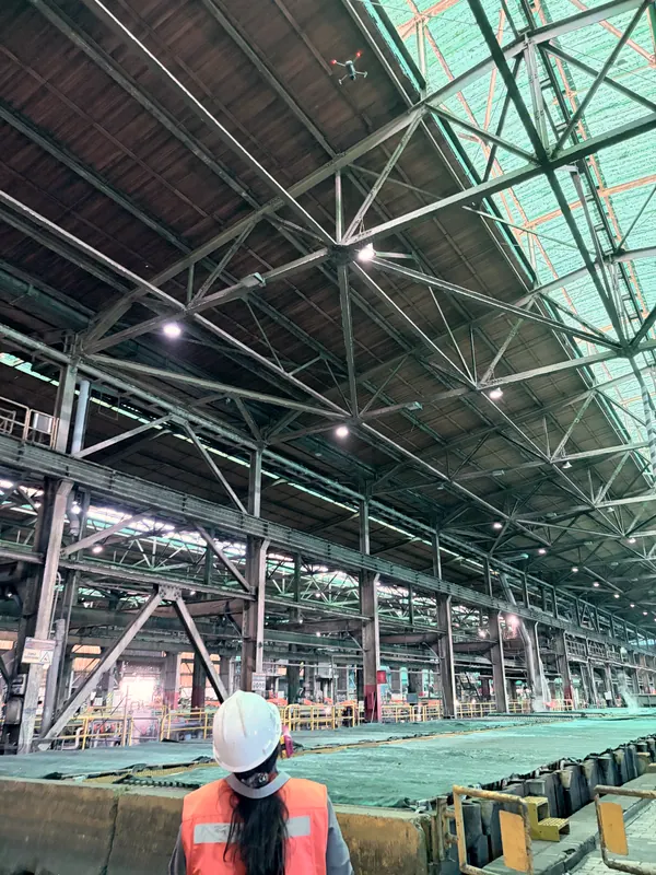 Nave industrial de estructura metálica con una trabajadora con casco al centro